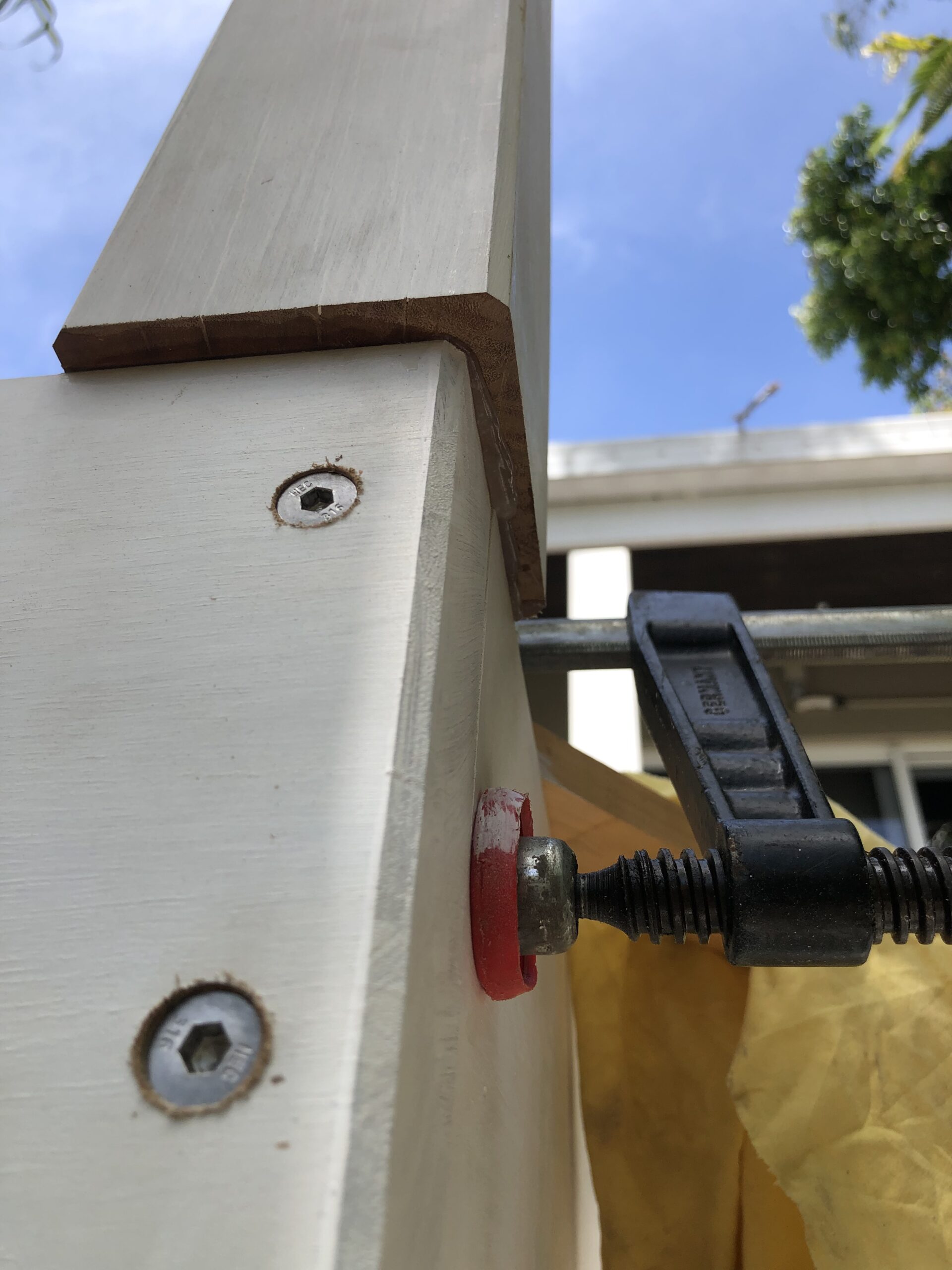 Close-up of a woodworking joint being clamped and secured, showing precise craftsmanship and assembly. Carpentry in Port Douglas